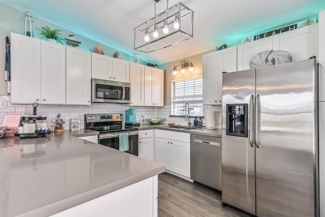 4126 Reeves Dr, Galveston, TX 77554 - kitchen with stainless steel appliances, a sink, white cabinets, and backsplash
