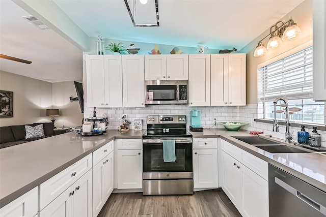 4126 Reeves Dr, Galveston, TX 77554 - kitchen featuring appliances with stainless steel finishes, a sink, tasteful backsplash, and white cabinetry