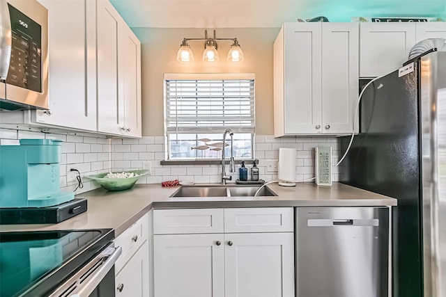 4126 Reeves Dr, Galveston, TX 77554 - kitchen with stainless steel appliances, a sink, backsplash, white cabinetry, and light countertops