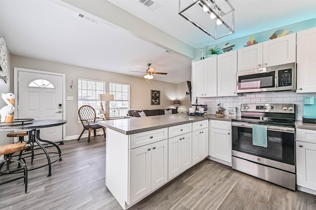 4126 Reeves Dr, Galveston, TX 77554 - kitchen featuring appliances with stainless steel finishes, a peninsula, and white cabinetry