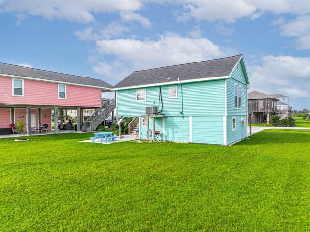 4126 Reeves Dr, Galveston, TX 77554 - back of house with stairs, a patio, a lawn, a shingled roof, and an outdoor fire pit