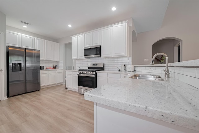 6718 Cleft Stone Dr, Houston, TX 77084 - kitchen featuring appliances with stainless steel finishes, a sink, white cabinetry, light stone countertops, and decorative backsplash