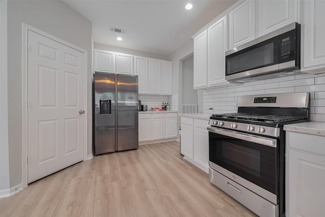 6718 Cleft Stone Dr, Houston, TX 77084 - kitchen featuring appliances with stainless steel finishes, light wood finished floors, white cabinetry, decorative backsplash, and recessed lighting