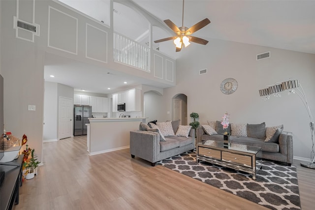 6718 Cleft Stone Dr, Houston, TX 77084 - living room with arched walkways, light wood finished floors, a high ceiling, a ceiling fan, and baseboards