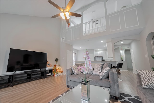 6718 Cleft Stone Dr, Houston, TX 77084 - living room with light wood-style floors, arched walkways, a ceiling fan, and a towering ceiling