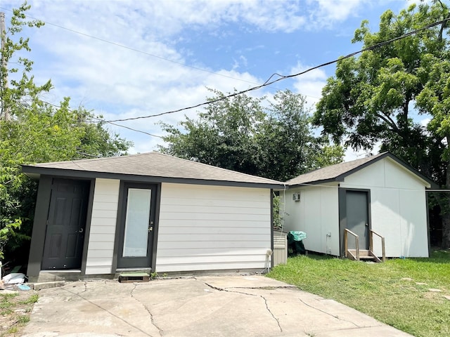 4118 Ebbtide Dr, Houston, TX 77045 - rear view of house featuring an outdoor structure, a shingled roof, a lawn, and a patio