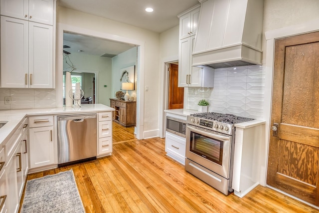 1708 S Park St, Brenham, TX 77833 - kitchen with stainless steel appliances, custom range hood, light wood-style floors, light countertops, and recessed lighting