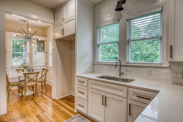 1708 S Park St, Brenham, TX 77833 - kitchen featuring light wood finished floors, a sink, backsplash, a chandelier, and plenty of natural light