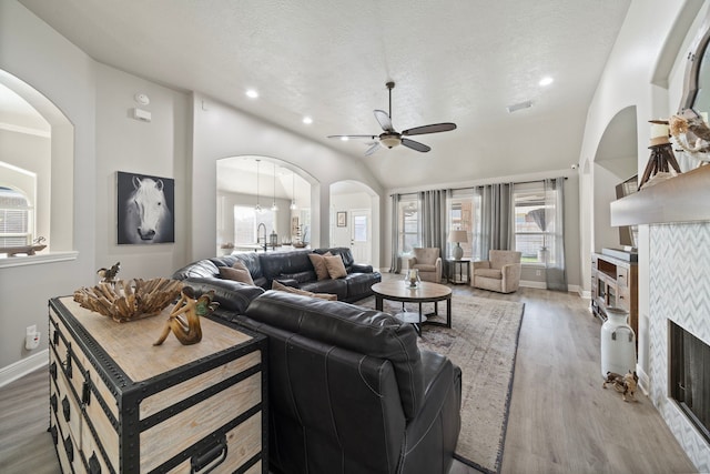 2517 Royal Terns Ct, League City, TX 77573 - living area featuring a ceiling fan, light wood-type flooring, arched walkways, a fireplace, and baseboards
