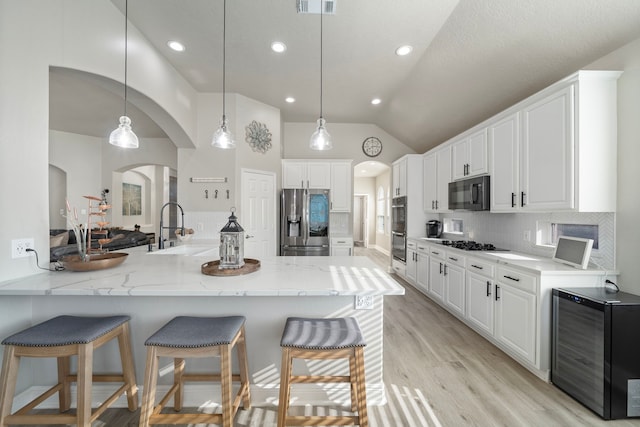 2517 Royal Terns Ct, League City, TX 77573 - kitchen featuring black appliances, a sink, wine cooler, arched walkways, and a breakfast bar area