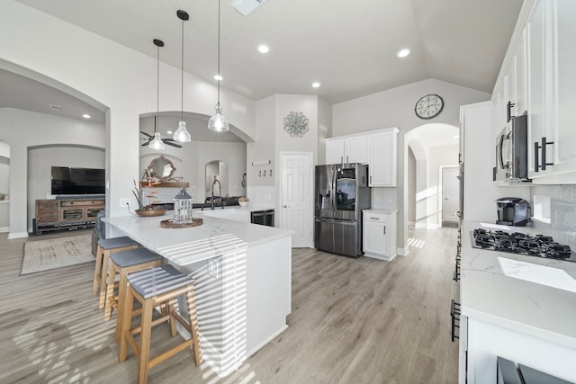 2517 Royal Terns Ct, League City, TX 77573 - kitchen featuring appliances with stainless steel finishes, arched walkways, light wood-style flooring, a sink, and lofted ceiling