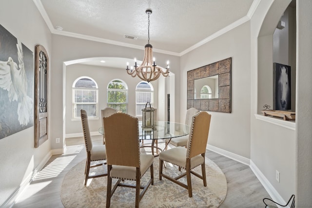 2517 Royal Terns Ct, League City, TX 77573 - dining area featuring arched walkways, light wood finished floors, a chandelier, crown molding, and a textured ceiling