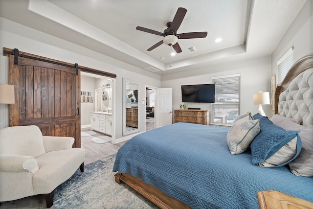 2517 Royal Terns Ct, League City, TX 77573 - bedroom with a tray ceiling, a barn door, wood finished floors, connected bathroom, and a ceiling fan