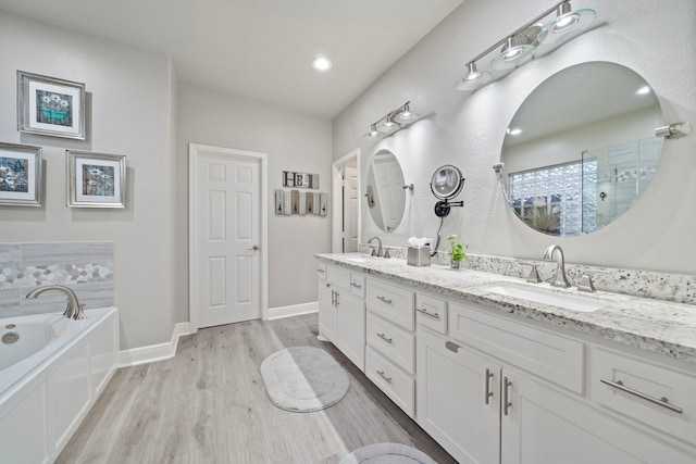 2517 Royal Terns Ct, League City, TX 77573 - bathroom featuring wood finished floors, a bath, double vanity, tiled shower, and baseboards