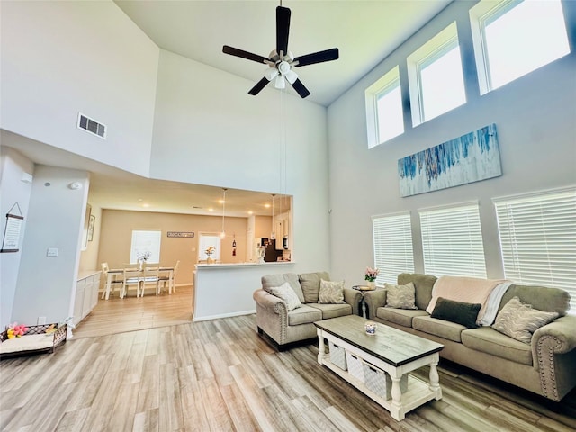 8835 Willet St, Baytown, TX 77521 - living area with light wood-style flooring, ceiling fan, a towering ceiling, and baseboards