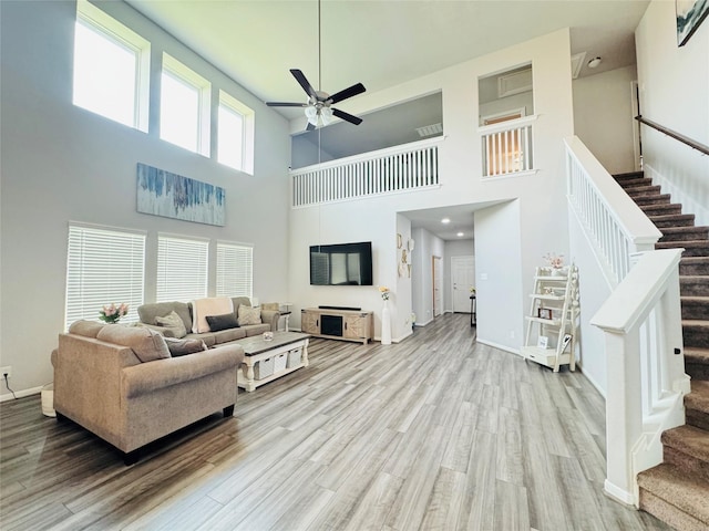 8835 Willet St, Baytown, TX 77521 - living area featuring ceiling fan, stairs, wood finished floors, a high ceiling, and baseboards