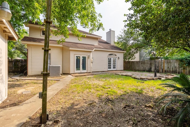 15034 Elstree Dr, Channelview, TX 77530 - back of property featuring french doors, central AC unit, a fenced backyard, and a chimney
