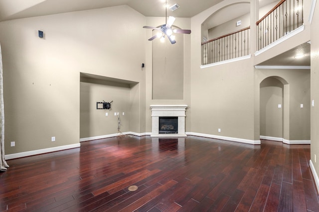 95 W Hullwood Cir, The Woodlands, TX 77389 - unfurnished living room featuring high vaulted ceiling, a ceiling fan, a glass covered fireplace, wood finished floors, and arched walkways