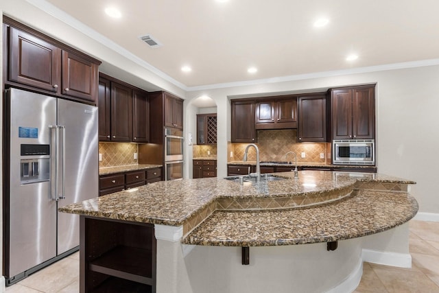 95 W Hullwood Cir, The Woodlands, TX 77389 - kitchen with stainless steel appliances, open shelves, a sink, dark stone counters, and dark brown cabinetry