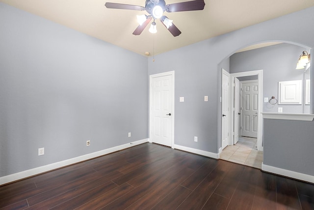 95 W Hullwood Cir, The Woodlands, TX 77389 - unfurnished bedroom with arched walkways, wood finished floors, baseboards, and ceiling fan