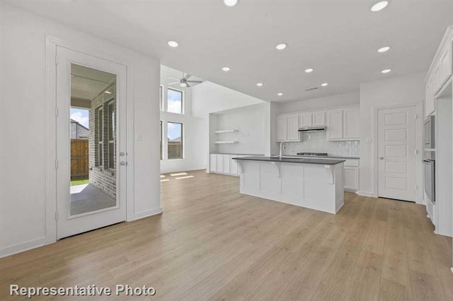 27007 Golden Isle Ln, Katy, TX 77493 - kitchen with white cabinets, stainless steel appliances, light wood finished floors, dark countertops, and ceiling fan