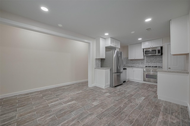 8302 Magna St, Houston, TX 77093 - kitchen featuring stainless steel appliances, backsplash, white cabinets, light wood-style flooring, and light stone countertops