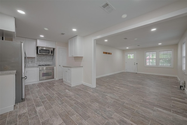 8302 Magna St, Houston, TX 77093 - kitchen featuring appliances with stainless steel finishes, open floor plan, baseboards, decorative backsplash, and white cabinetry