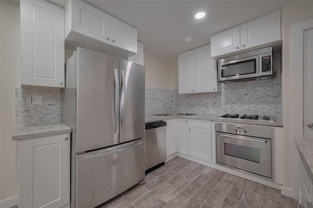 8302 Magna St, Houston, TX 77093 - kitchen with appliances with stainless steel finishes, a sink, white cabinets, backsplash, and recessed lighting