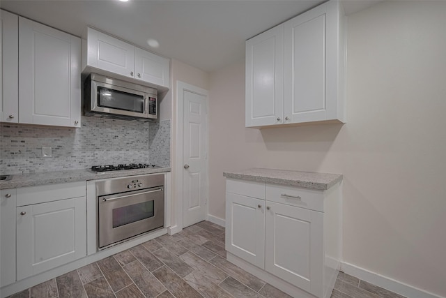 8302 Magna St, Houston, TX 77093 - kitchen featuring stainless steel appliances, baseboards, white cabinetry, tasteful backsplash, and recessed lighting