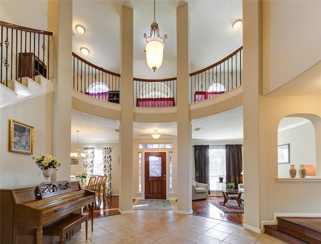 21714 Honeysuckle Grove Ln, Richmond, TX 77469 - tiled foyer featuring a chandelier, a towering ceiling, stairs, baseboards, and arched walkways