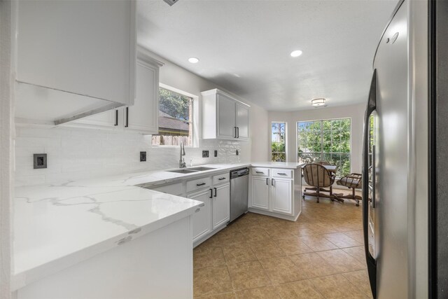 14531 County Cress Dr, Houston, TX 77047 - kitchen with a peninsula, stainless steel appliances, a sink, decorative backsplash, and light tile patterned flooring