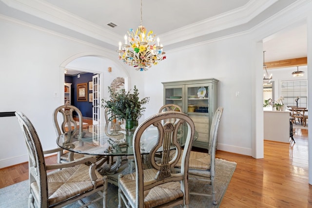 4021 Glenshire St, Houston, TX 77025 - dining area with a chandelier, light wood finished floors, arched walkways, crown molding, and baseboards
