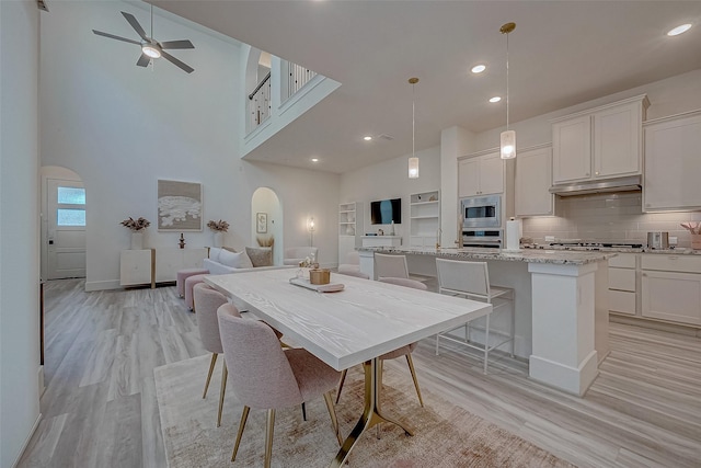 5038 Galahad Ct, Missouri City, TX 77459 - dining space with light wood-type flooring, a high ceiling, arched walkways, ceiling fan, and recessed lighting