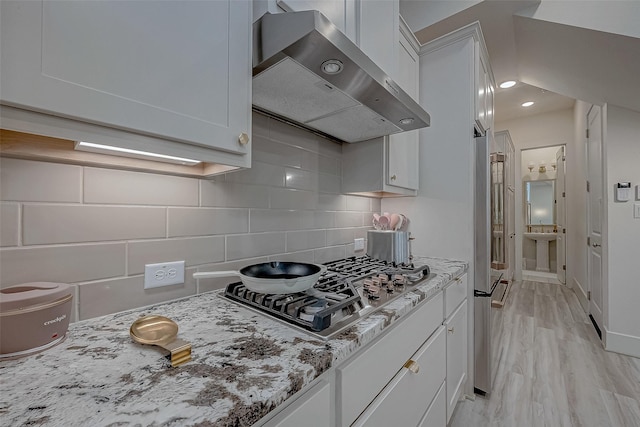 5038 Galahad Ct, Missouri City, TX 77459 - kitchen with extractor fan, stainless steel gas cooktop, decorative backsplash, white cabinetry, and light stone countertops