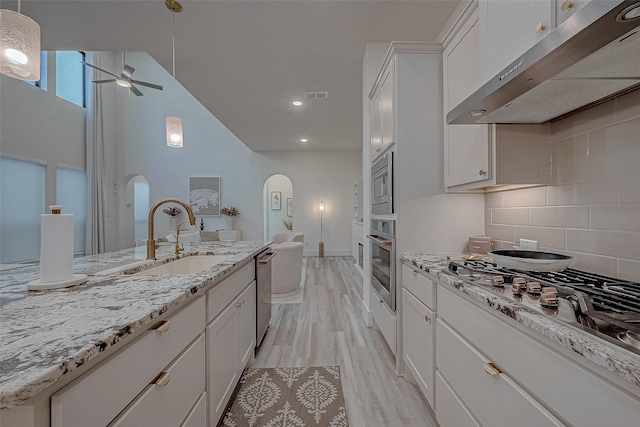 5038 Galahad Ct, Missouri City, TX 77459 - kitchen with under cabinet range hood, stainless steel appliances, a sink, ceiling fan, and arched walkways