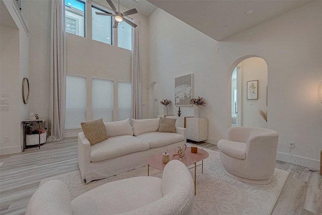 5038 Galahad Ct, Missouri City, TX 77459 - living room featuring a towering ceiling, arched walkways, light wood-type flooring, a ceiling fan, and baseboards