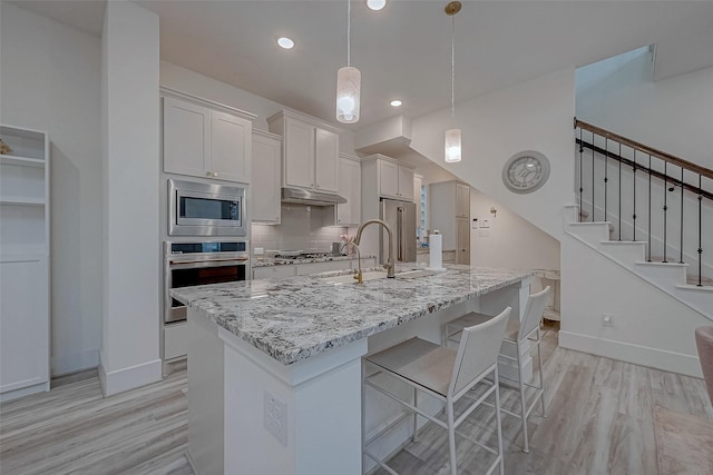 5038 Galahad Ct, Missouri City, TX 77459 - kitchen featuring appliances with stainless steel finishes, under cabinet range hood, baseboards, light wood-style floors, and recessed lighting