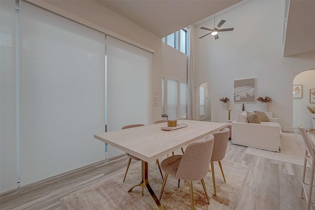 5038 Galahad Ct, Missouri City, TX 77459 - dining area featuring arched walkways, light wood-type flooring, ceiling fan, and a high ceiling