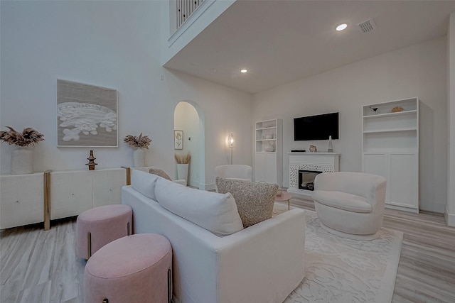5038 Galahad Ct, Missouri City, TX 77459 - living room featuring arched walkways, light wood finished floors, a fireplace, recessed lighting, and baseboards