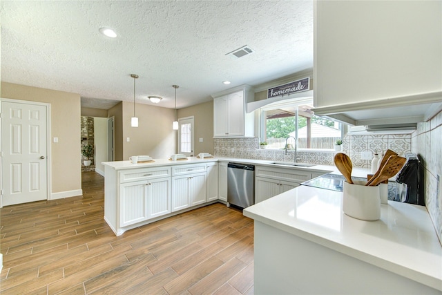 15203 Mcconn St, Houston, TX 77598 - kitchen featuring stainless steel dishwasher, a sink, a peninsula, decorative backsplash, and light wood-style floors