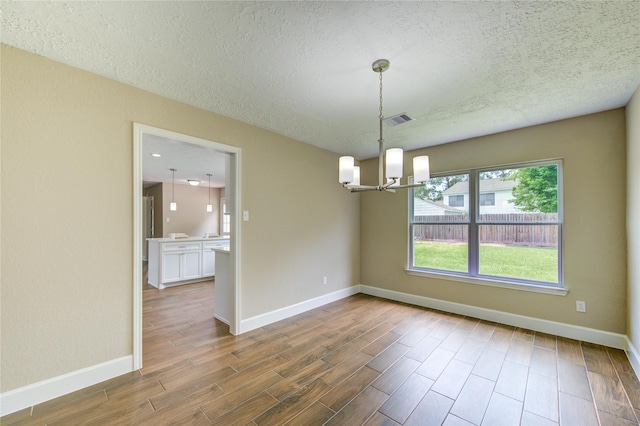 15203 Mcconn St, Houston, TX 77598 - empty room with a chandelier, a textured ceiling, wood finished floors, and baseboards