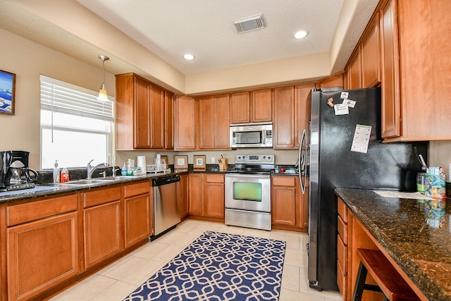 115 Mar Vista Ct, Surfside Beach, TX 77541 - kitchen with appliances with stainless steel finishes, a sink, brown cabinetry, dark stone counters, and recessed lighting