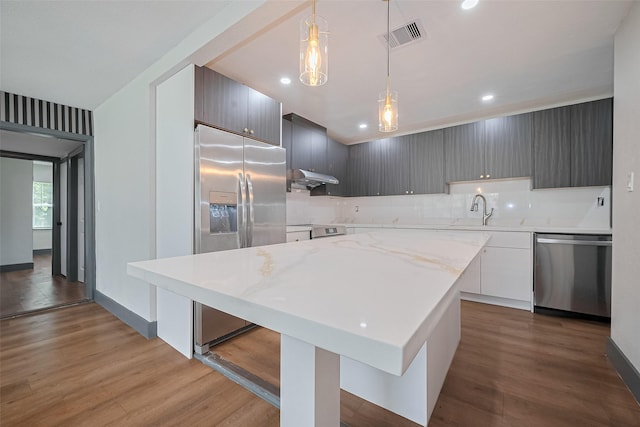 6058 Lyndhurst Dr, Houston, TX 77033 - kitchen with stainless steel appliances, under cabinet range hood, wood finished floors, a sink, and hanging light fixtures