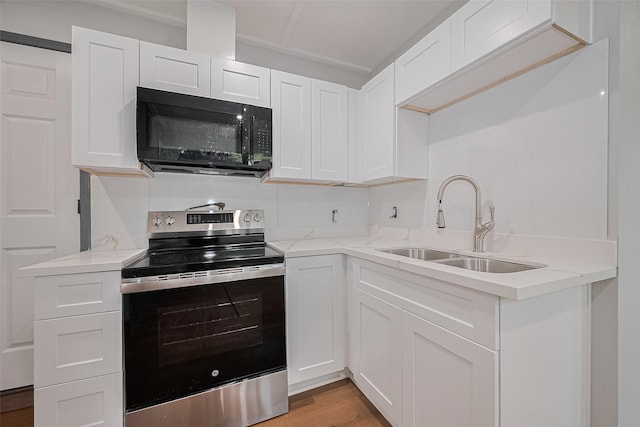 6058 Lyndhurst Dr, Houston, TX 77033 - kitchen with black microwave, stainless steel range with electric stovetop, a sink, white cabinetry, and light stone countertops
