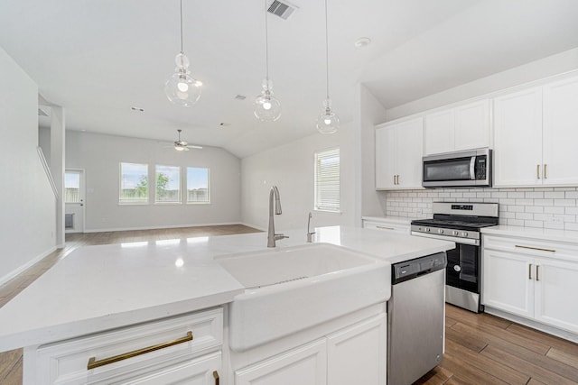 7714 Squall Ln, Baytown, TX 77523 - kitchen featuring appliances with stainless steel finishes, a sink, lofted ceiling, wood finished floors, and backsplash