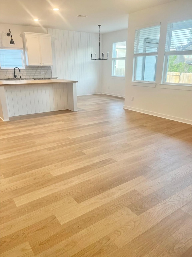 12531 Hilltop Mill Rd, Magnolia, TX 77354 - kitchen with a chandelier, light wood finished floors, white cabinets, and open floor plan