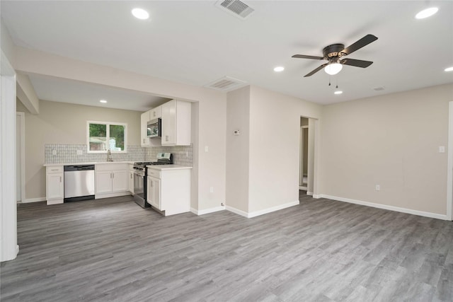 9409 Fairland Dr, Houston, TX 77051 - kitchen featuring appliances with stainless steel finishes, open floor plan, backsplash, wood finished floors, and white cabinets