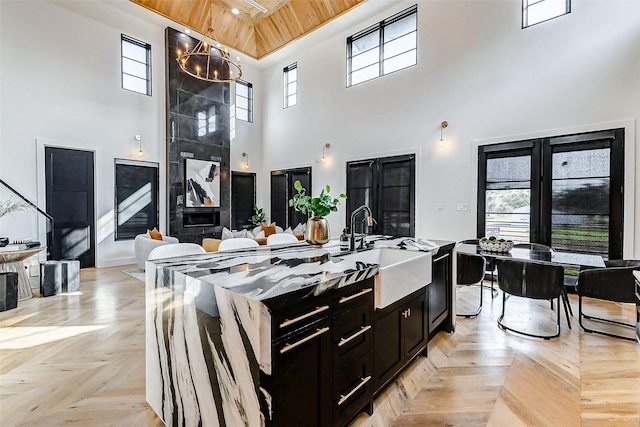 1030 Voight St, Houston, TX 77009 - kitchen featuring a sink, a high ceiling, dark cabinetry, wooden ceiling, and a kitchen island with sink