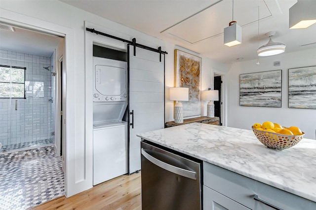 1030 Voight St, Houston, TX 77009 - kitchen with stacked washer and clothes dryer, stainless steel dishwasher, light wood-type flooring, light stone counters, and a barn door