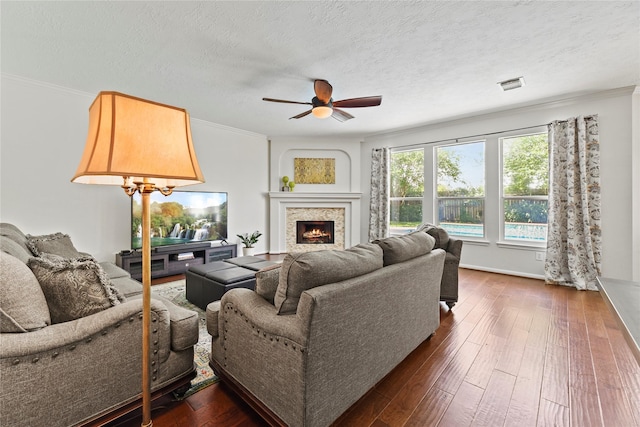 4019 Bellinger Way, Missouri City, TX 77459 - living room with a ceiling fan, crown molding, a warm lit fireplace, dark wood-style floors, and a textured ceiling